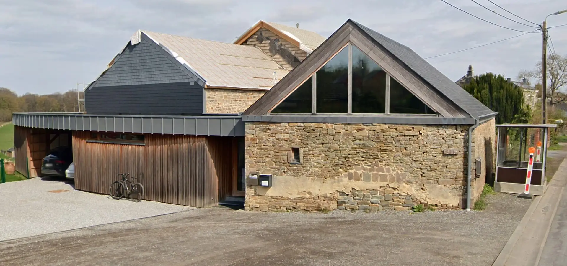 Bâtiment de l'Espace Médical du Condroz à Lagrange : façade en pierre, grand pignon vitré et annexe en bois